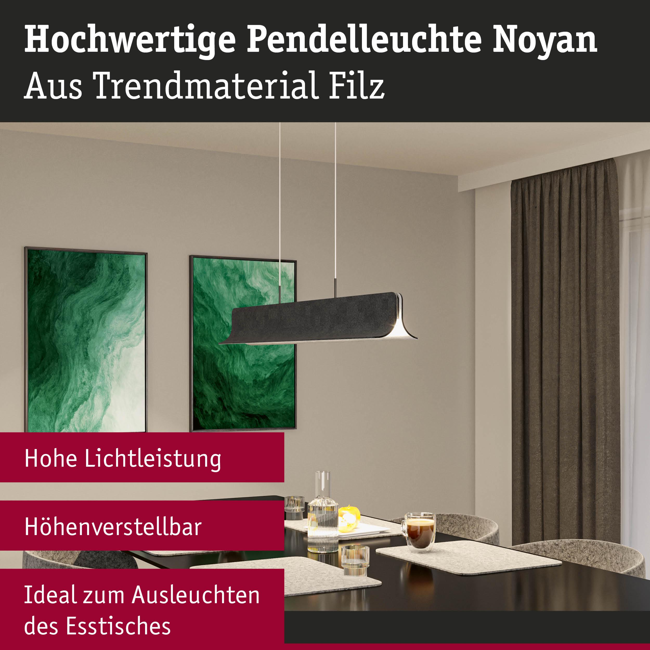 Schwarze Pendelleuchte über einem Esstisch mit grünen Bildern an der Wand.