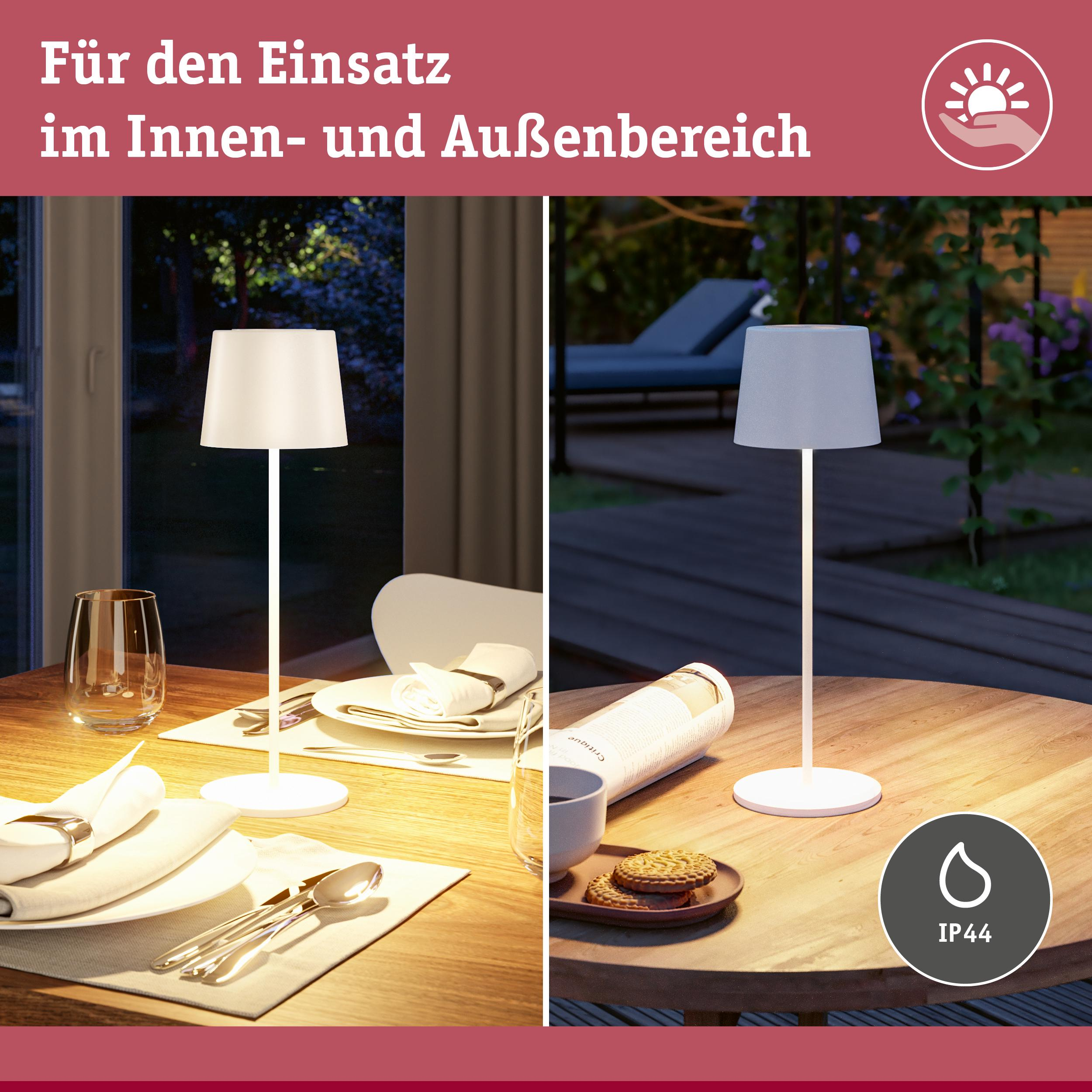 Lampa wewnętrzna/zewnętrzna na stole z zastawą i ciastkami.