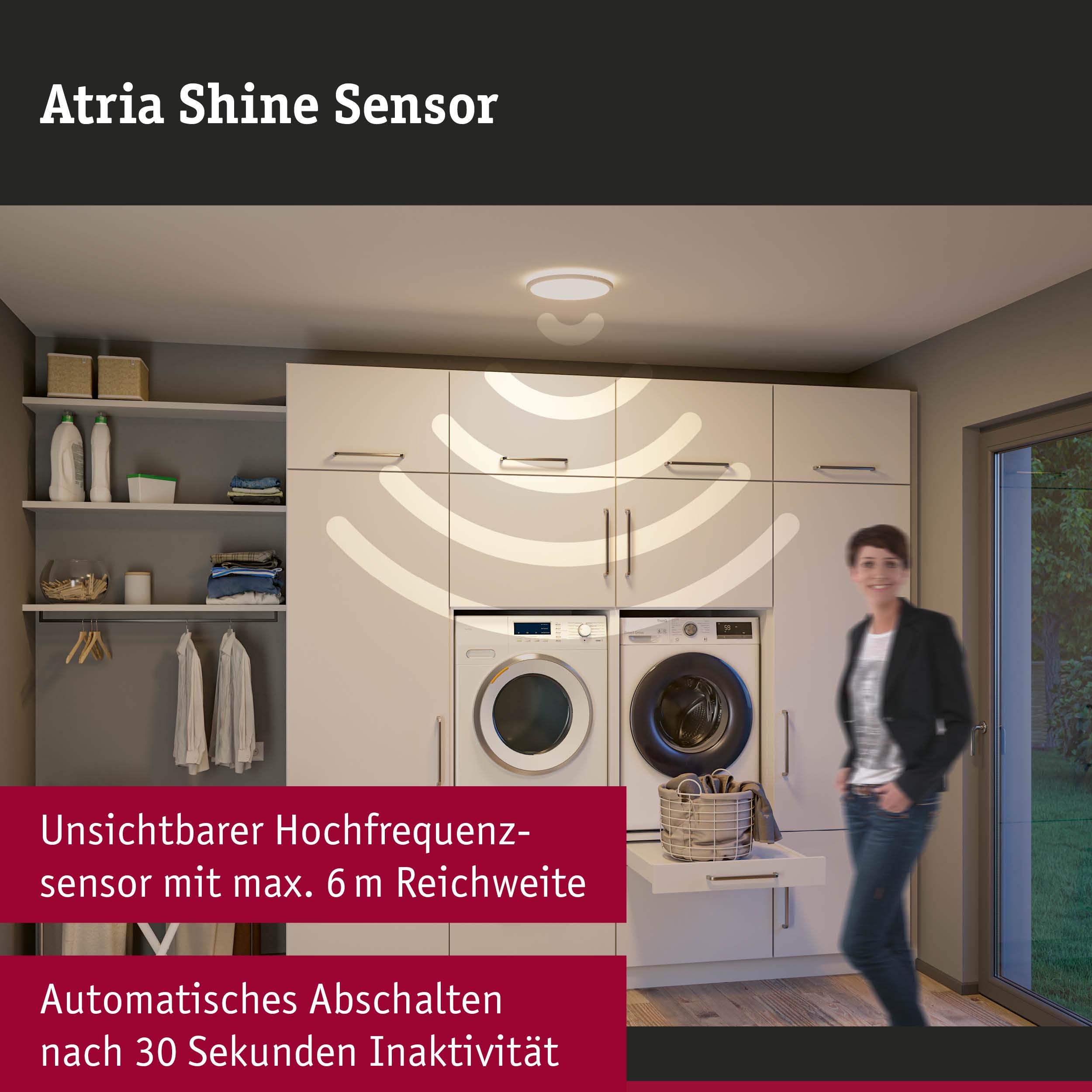 Ein Raum mit Waschmaschinen und einer Frau, die lächelt. Ein Sensor an der Decke.