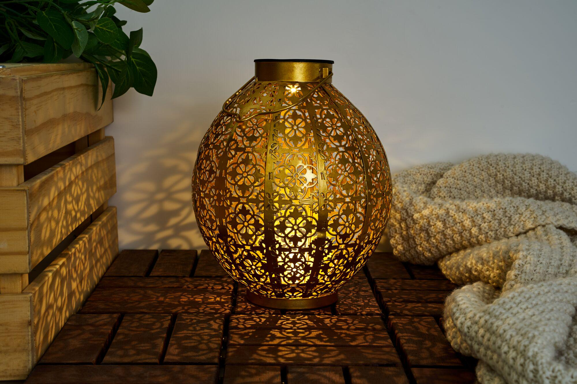 Złota latarnia o misterym wzorze świeci na drewnianym stole obok koca.