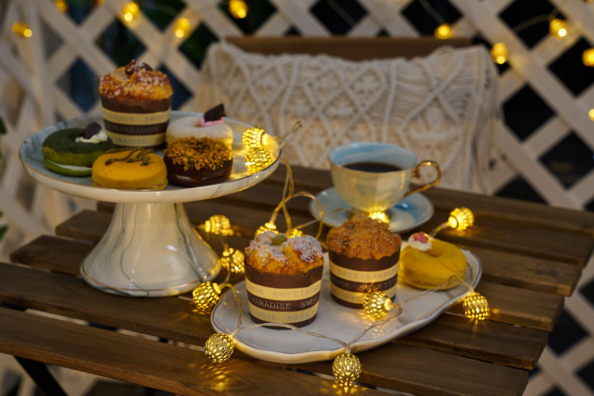 Babeczki i pączki na stole ze sznurkiem świateł.