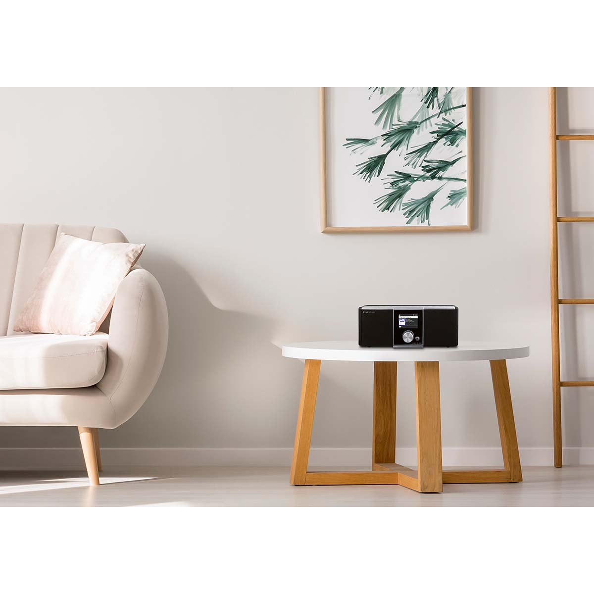 A black radio sits on a round white table next to a sofa and a picture.