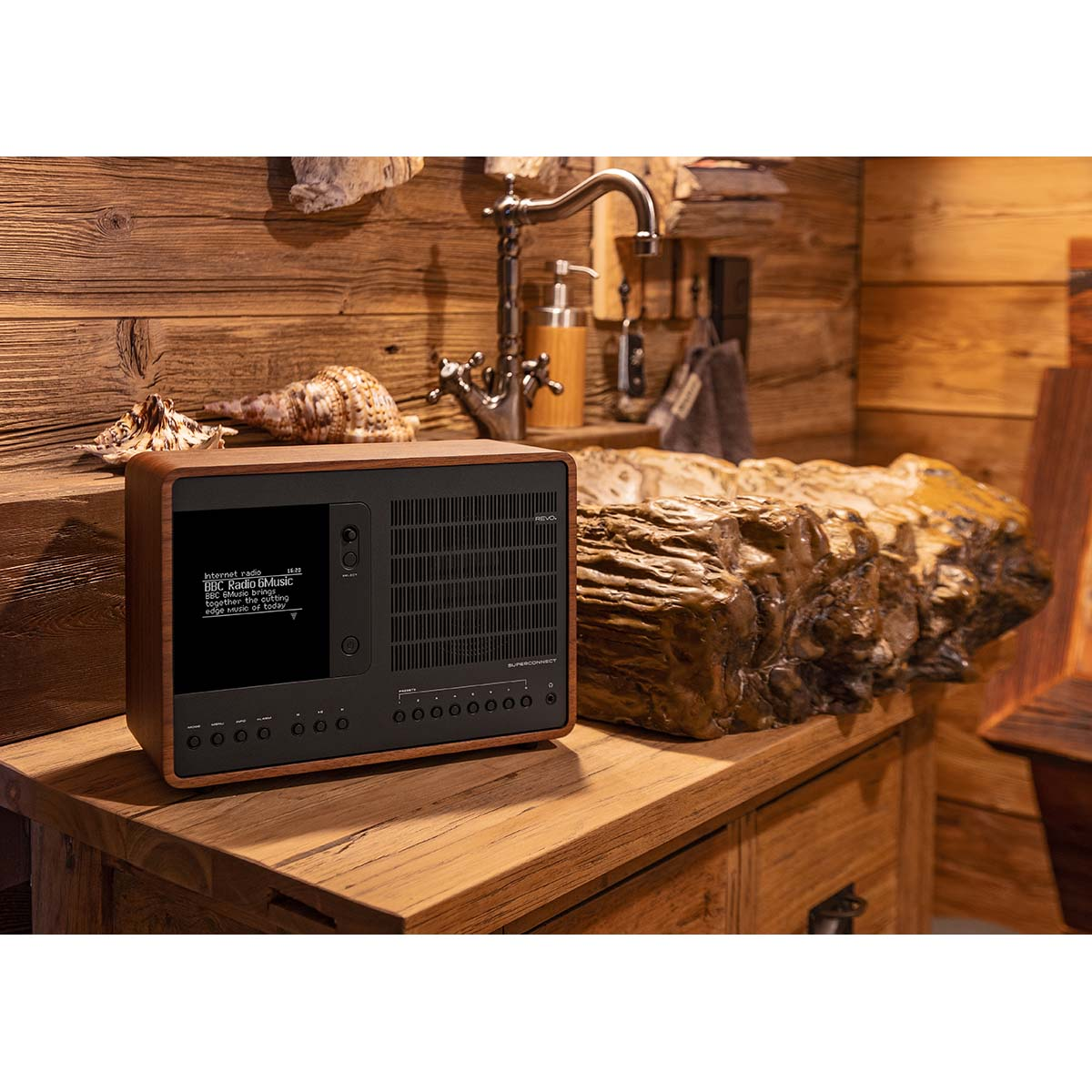 A wooden radio with a screen plays BBC Radio 6Music on a wooden table.