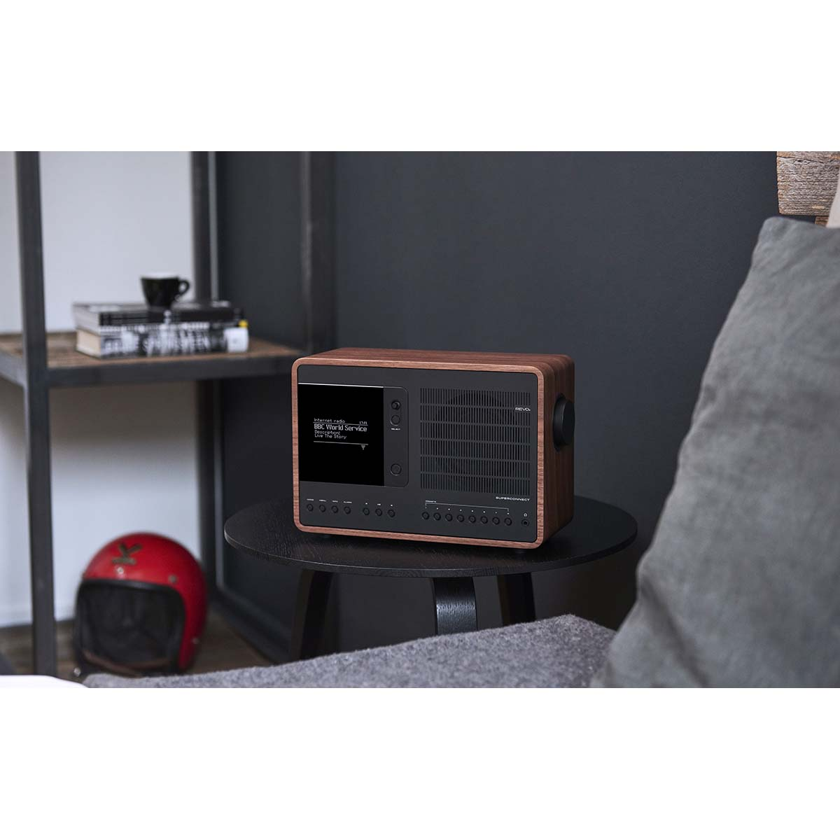 A wooden radio with a black screen sits on a round table next to a red helmet.
