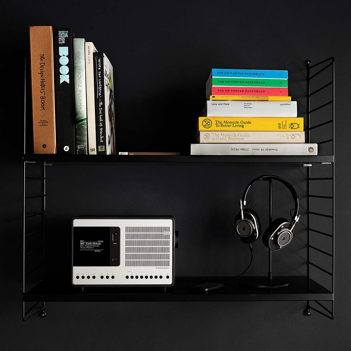 Books and headphones on a black shelf. A radio sits on the left.