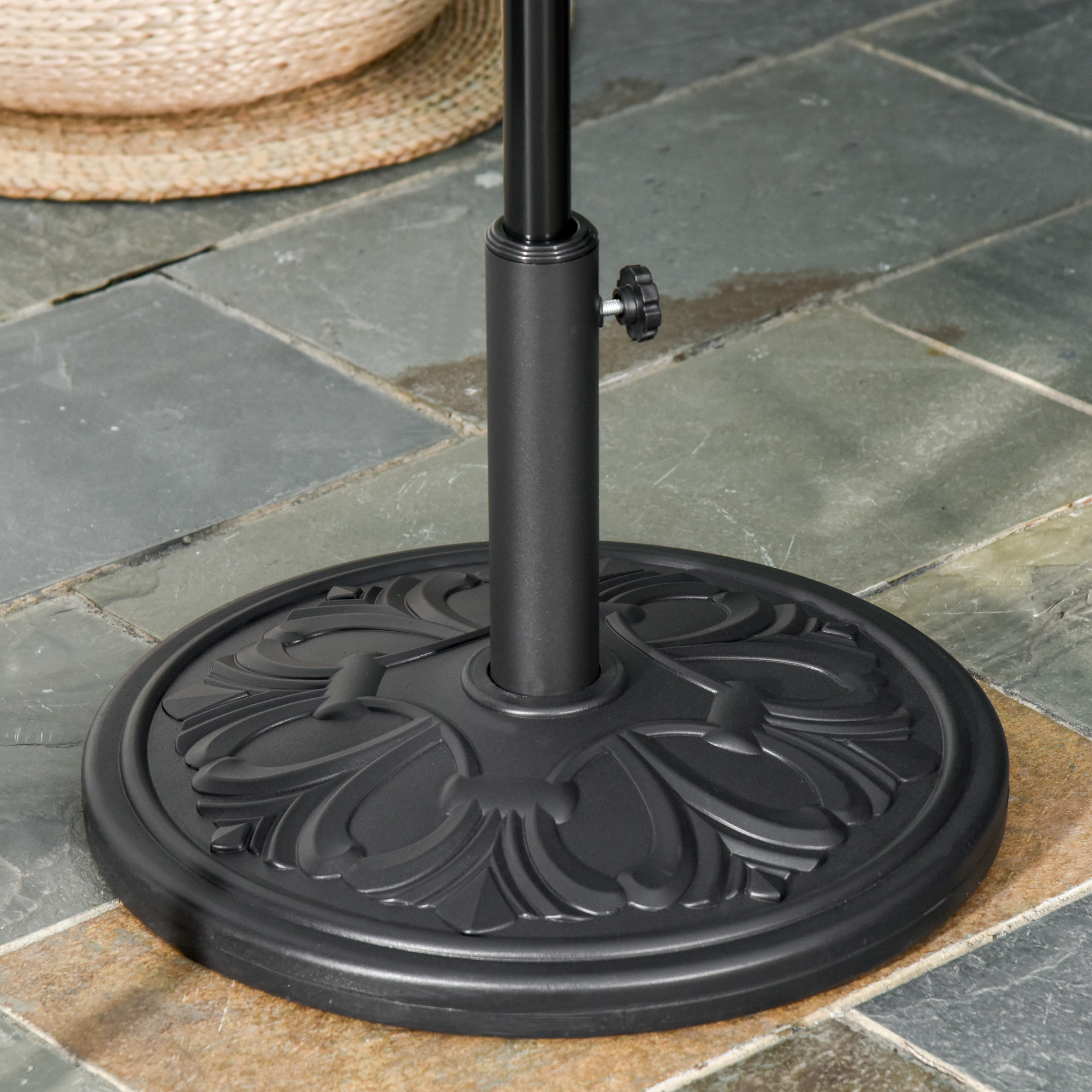 Un soporte de sombrilla negro con patrón en relieve sobre suelo de baldosas.