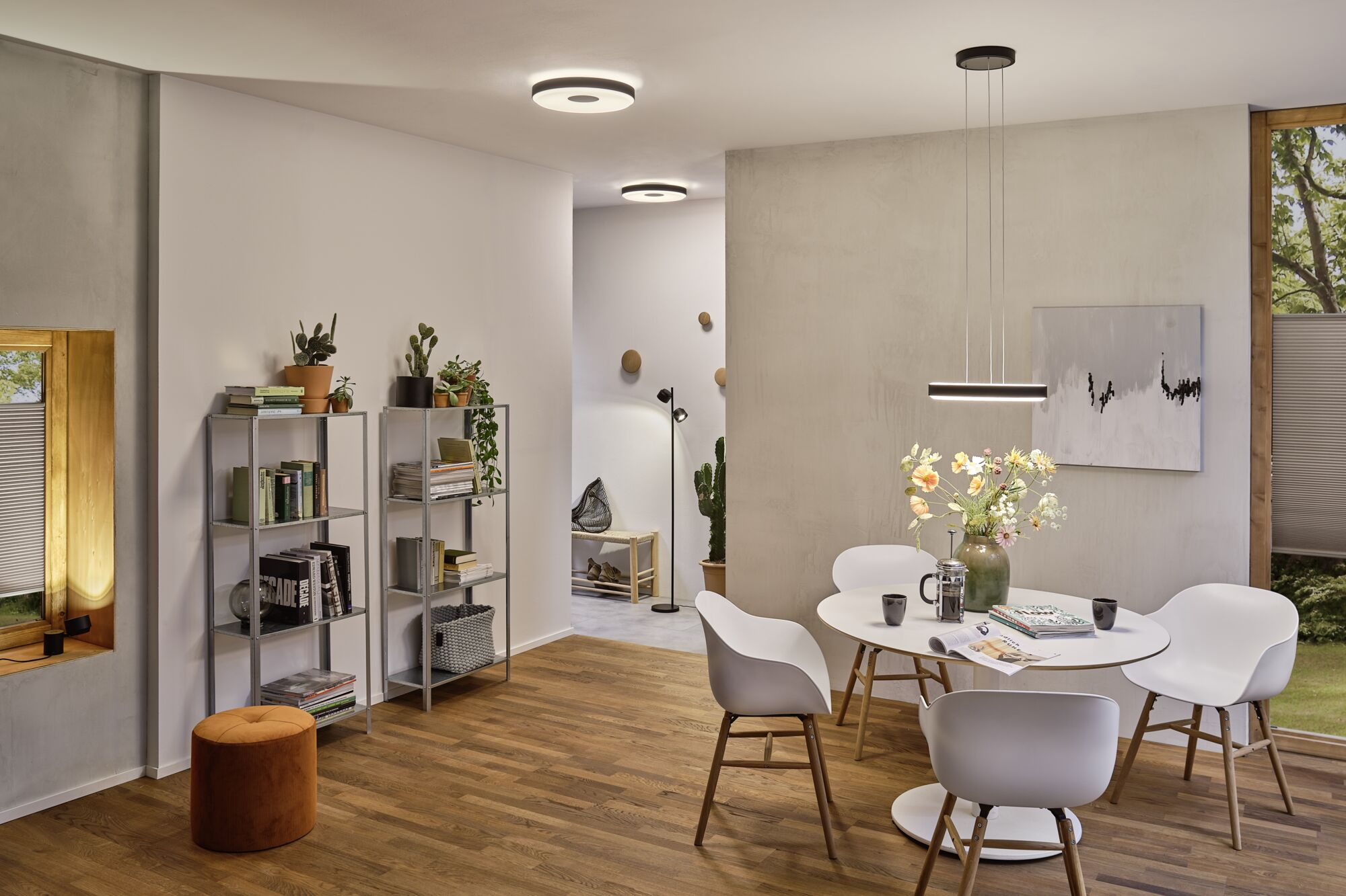 Ein helles Wohnzimmer mit Esstisch, Stühlen und einem Bücherregal.