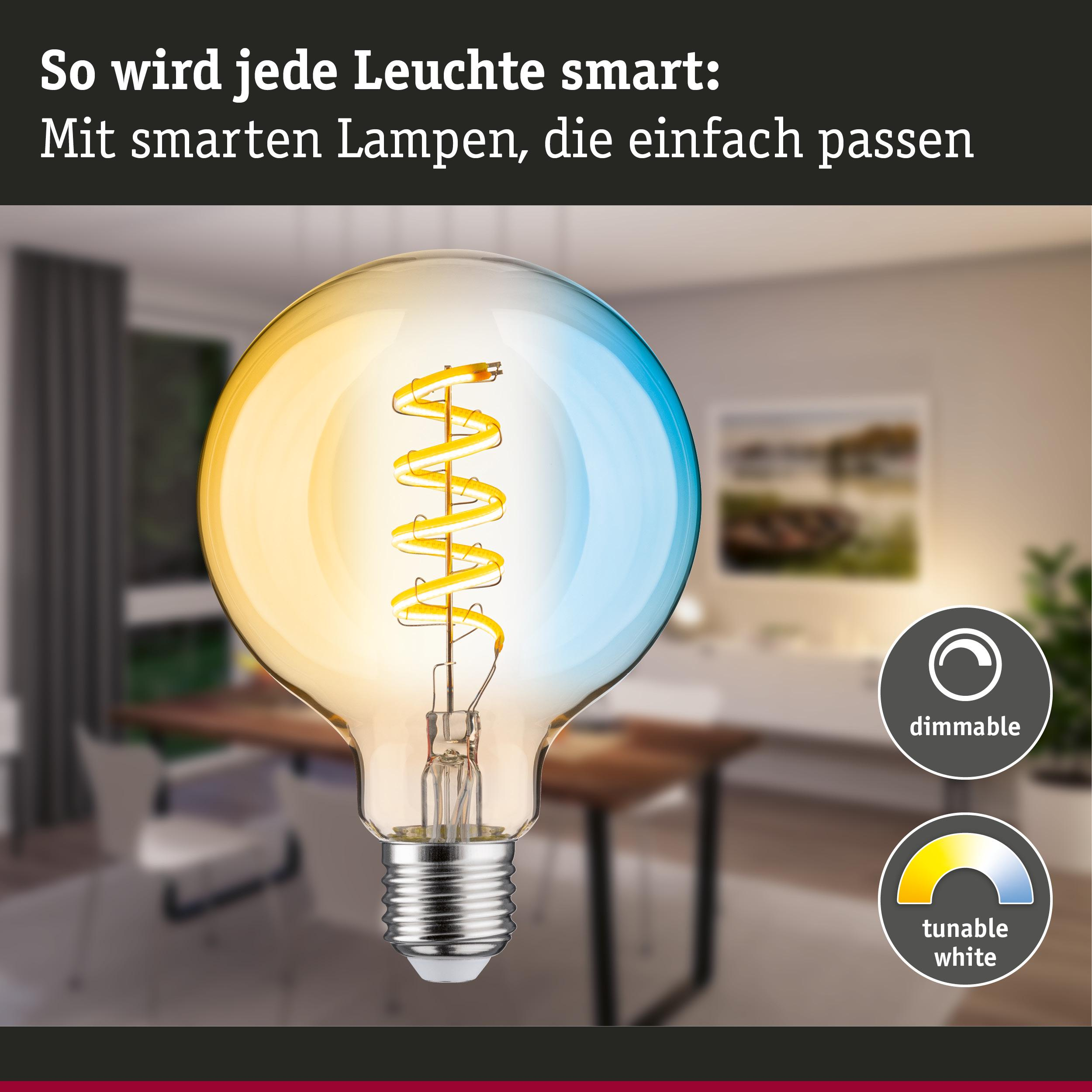 Eine smarte Glühbirne mit leuchtendem, gewickeltem Glühfaden in einem Wohnzimmer.