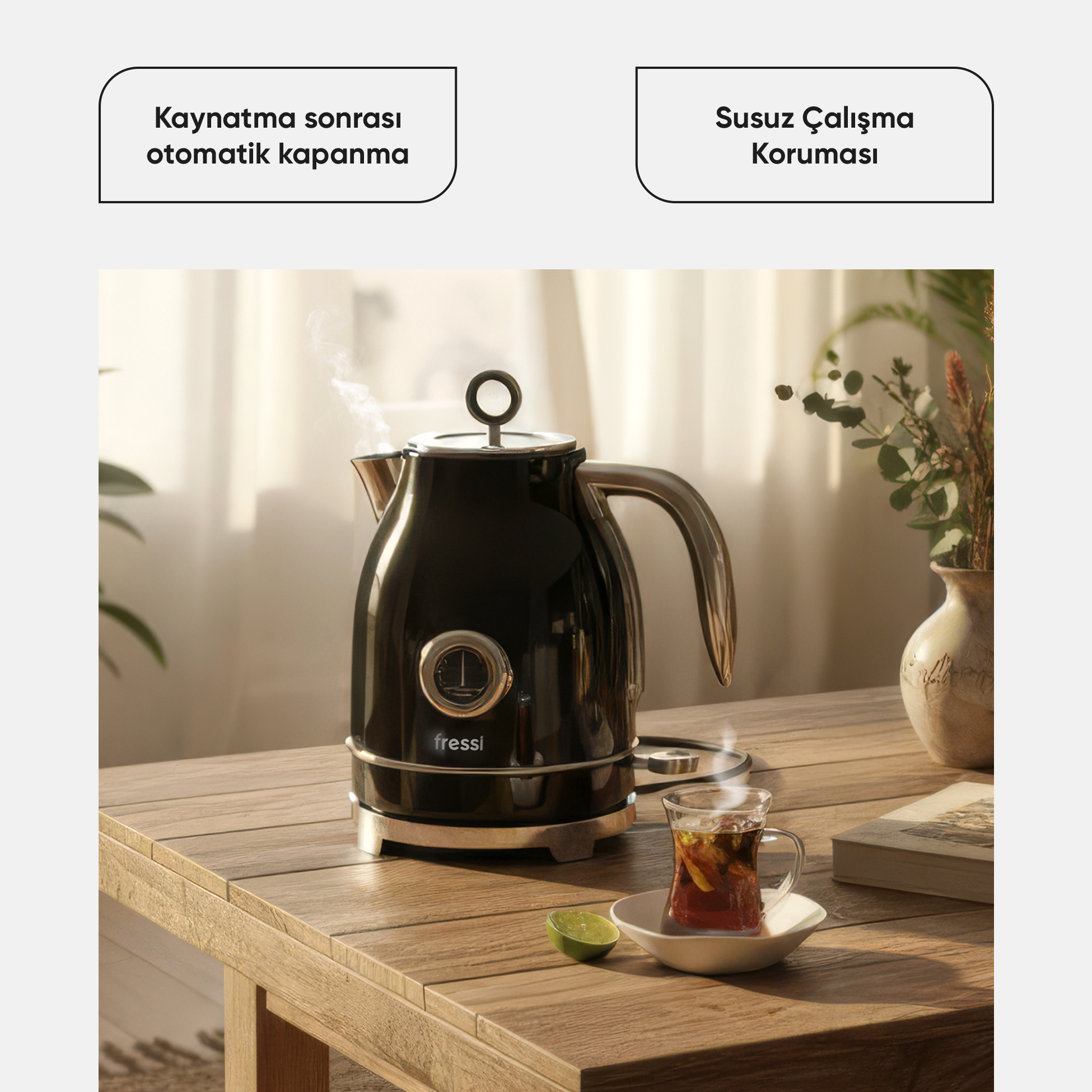 Buhar çıkan siyah su ısıtıcı, yanında bir bardak çay ve limon dilimi.
