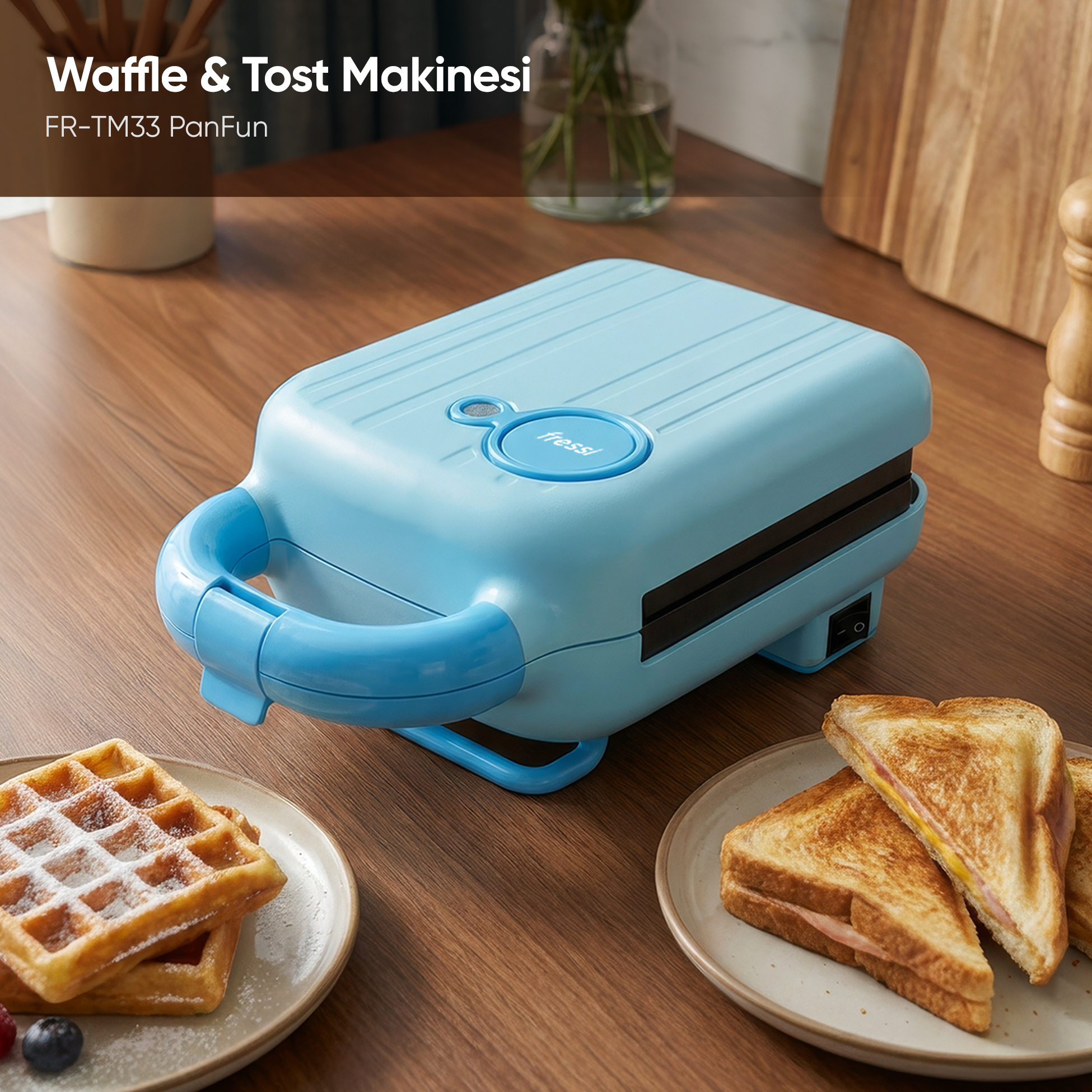 Açık mavi waffle ve sandviç makinesi, waffle ve sandviçlerin yanında ahşap bir masada duruyor.