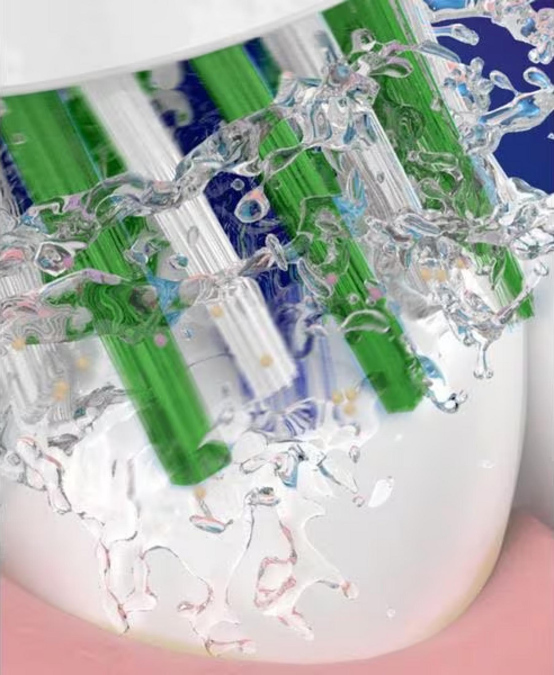 Zielone i białe włosie szczoteczki do zębów z pluskami wody.