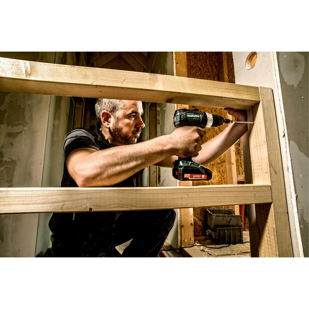 Un uomo usa un trapano avvitatore a batteria per avvitare nel telaio di legno.
