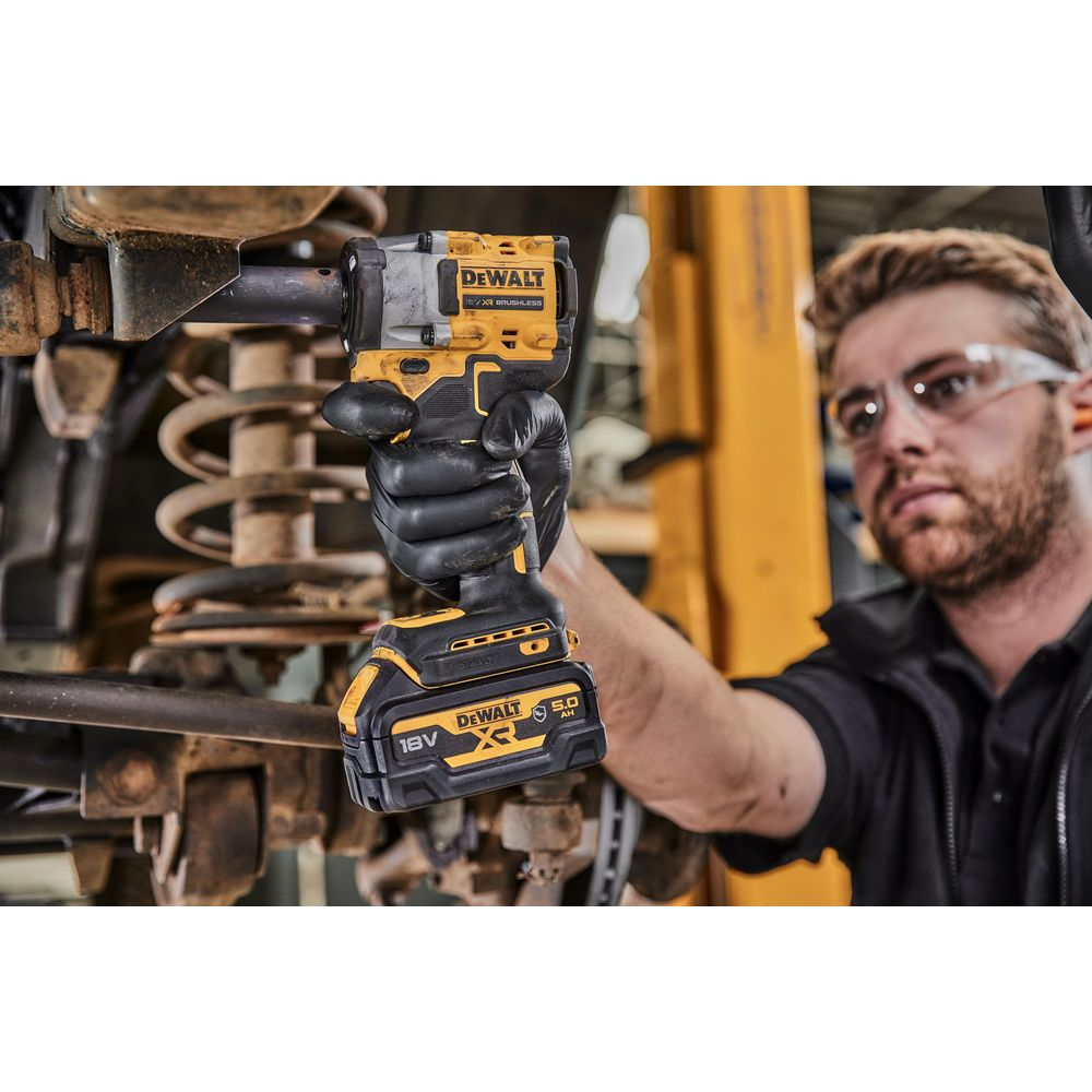 Ein Mann mit Schutzbrille benutzt einen gelben und schwarzen Dewalt Schlagschrauber an einem Auto.