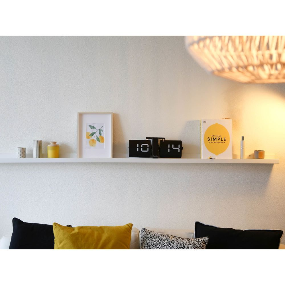 Una mensola con decorazioni: quadro di arance, orologio, libro, candele.