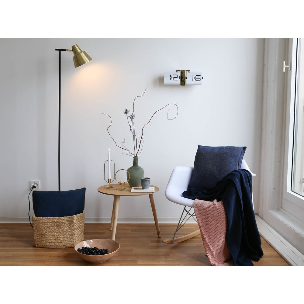 Un espace de vie moderne avec chaise blanche, couvertures, panier et lampe.