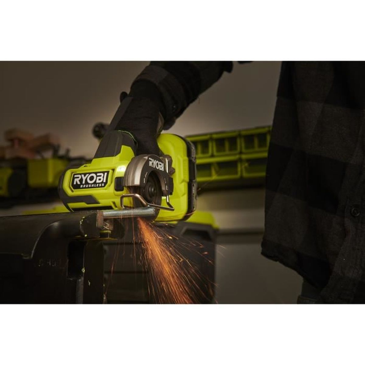 Une main gantée utilise une meuleuse d'angle Ryobi jaune, produisant des étincelles.
