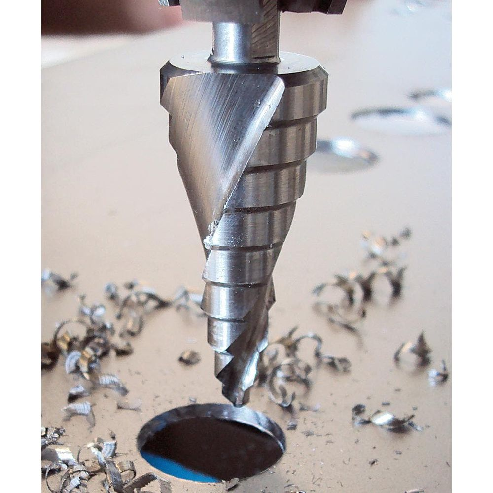 Ein Stufenbohrer bohrt ein Loch in Metall und erzeugt Metallspäne.