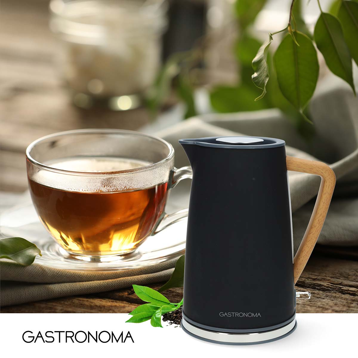 Eine schwarze Teekanne mit Holzgriff neben einer Tasse Tee.