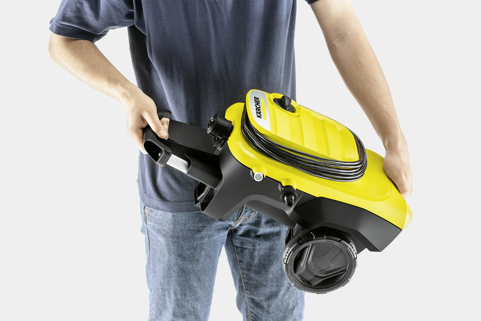Uomo che tiene un'idropulitrice Karcher gialla con manico e ruote nere.