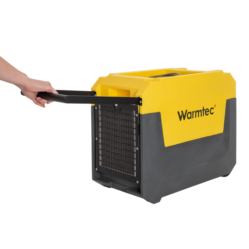 Ręka ciągnie żółty i szary osuszacz Warmtec z wysuwanym uchwytem.