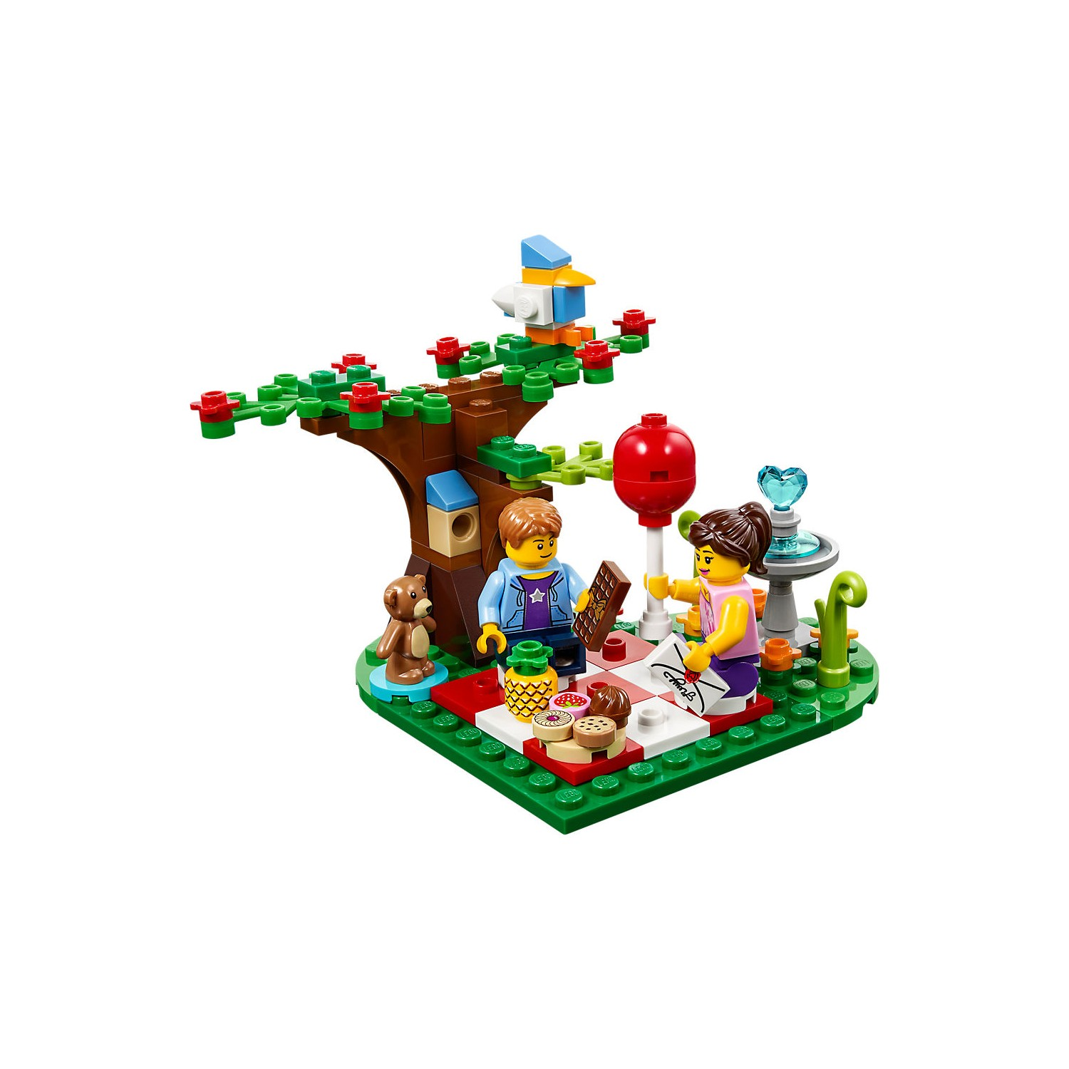 Bir kuş, köpek ve çeşmenin olduğu Lego ağacının altında piknik yapan iki Lego figürü.