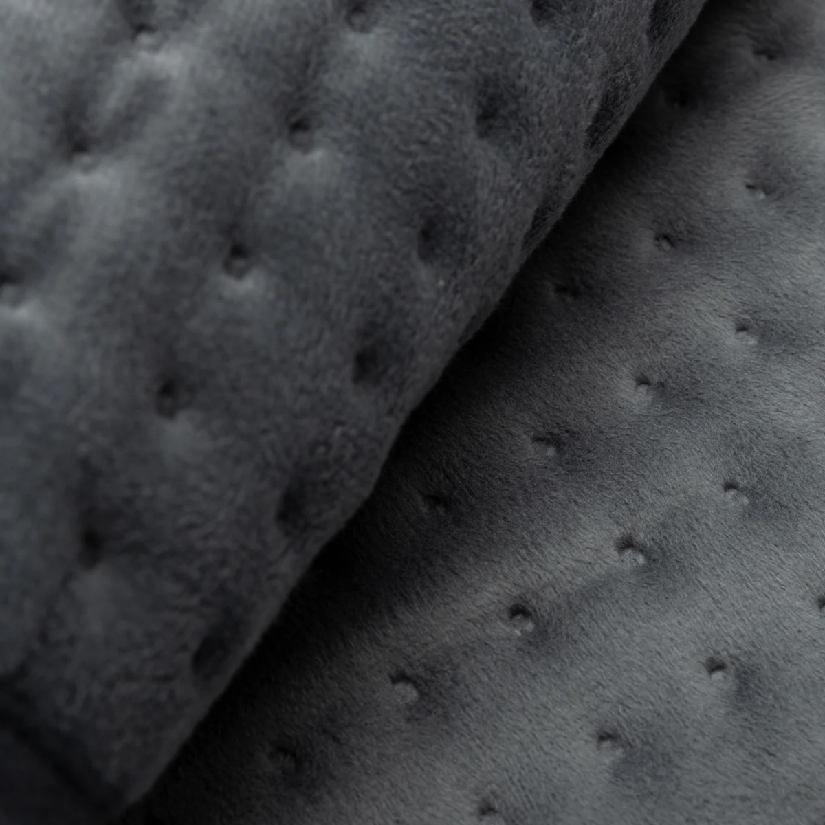 Tela gris oscura acolchada con textura suave y aterciopelada. Dos capas de tela dobladas una sobre otra.
