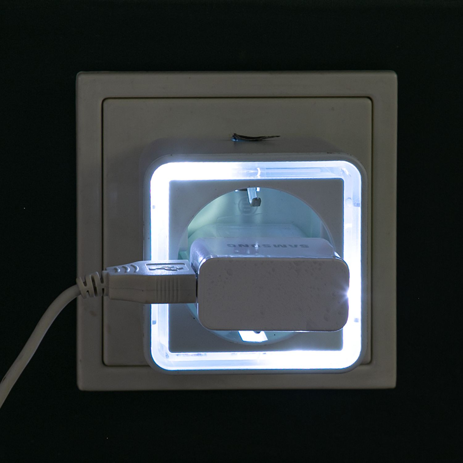 Ein weier USB-Adapter, der in eine weie Steckdose mit blauer LED-Umrandung gesteckt ist.