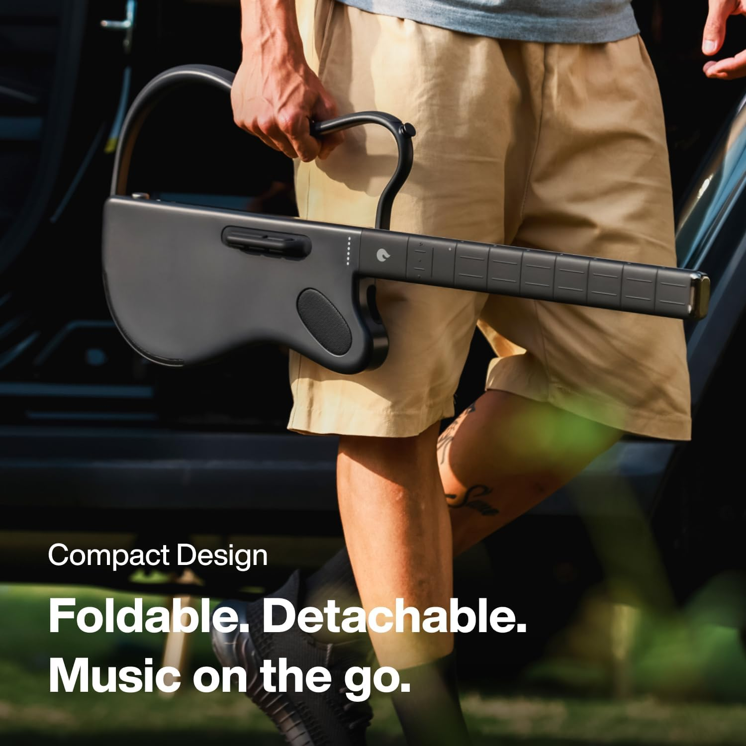 Man holding a black, foldable, electric guitar with a curved handle. Text: Compact Design.