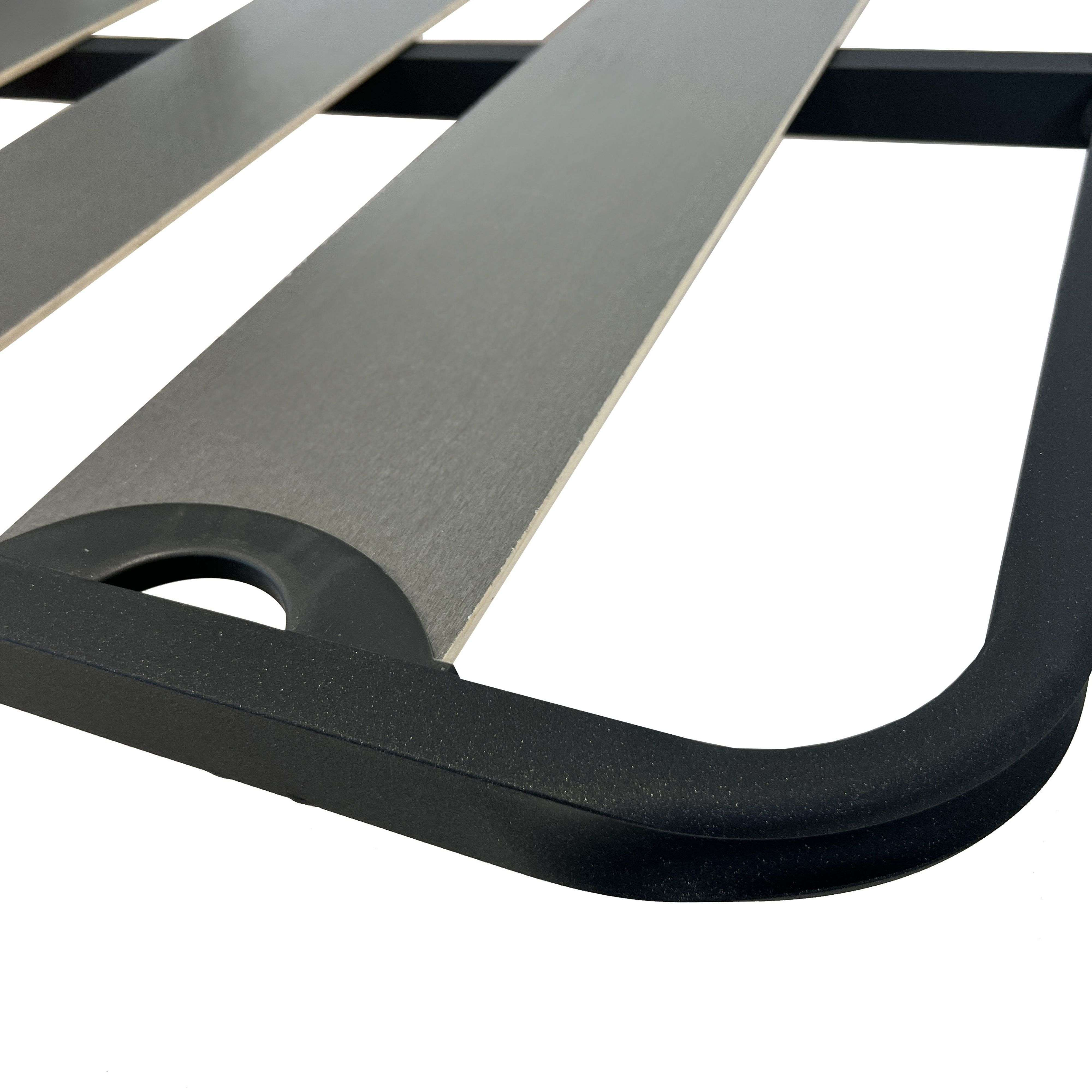 Un marco de metal negro sostiene listones de madera grises de una base de cama.