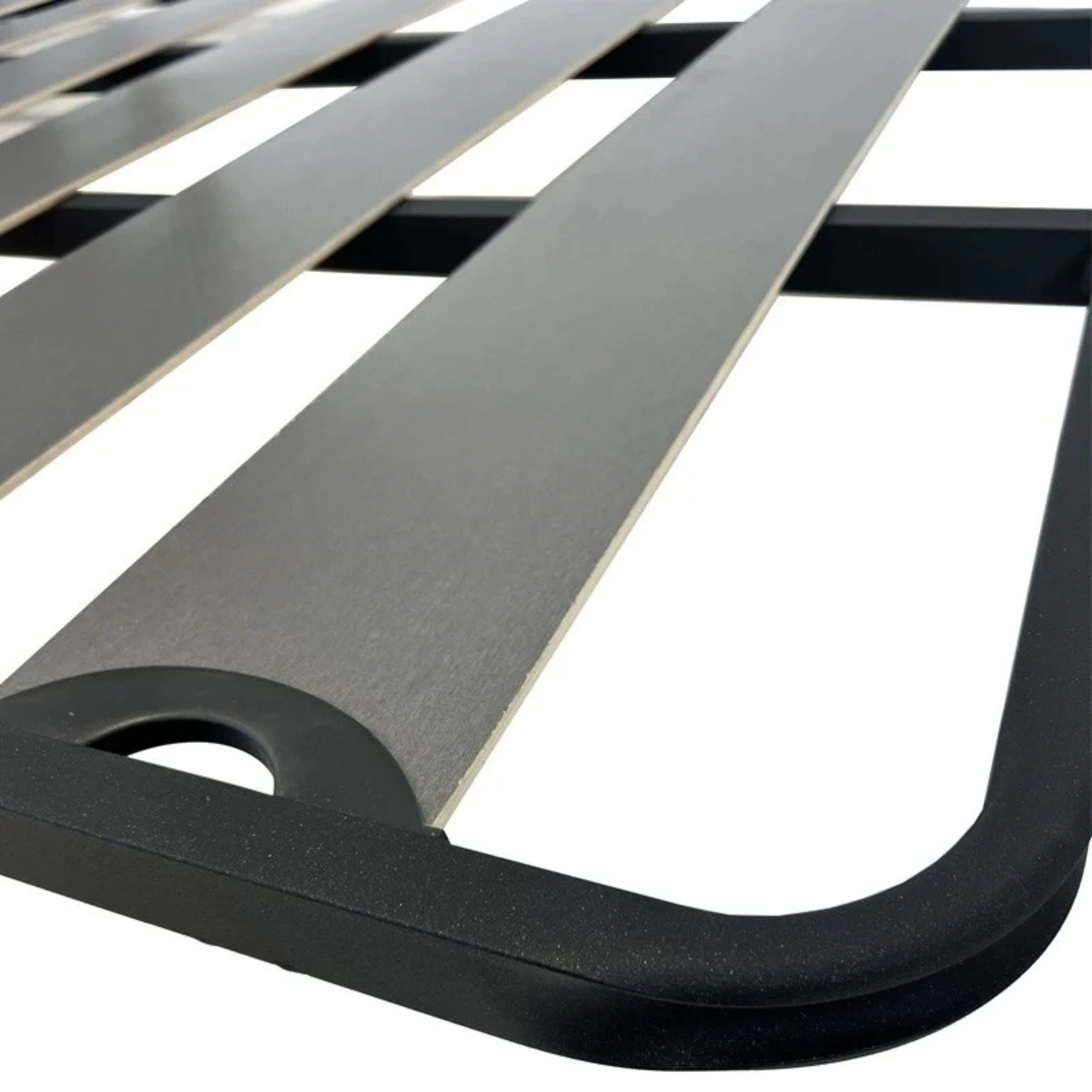 Primer plano de una base de cama de metal negro con listones grises paralelos.