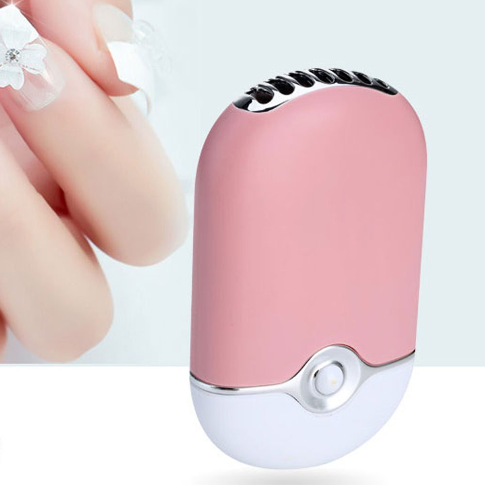 Pinker Mini-Ventilator mit silbernen Akzenten, gehalten nahe einer Hand mit verzierten Nägeln.