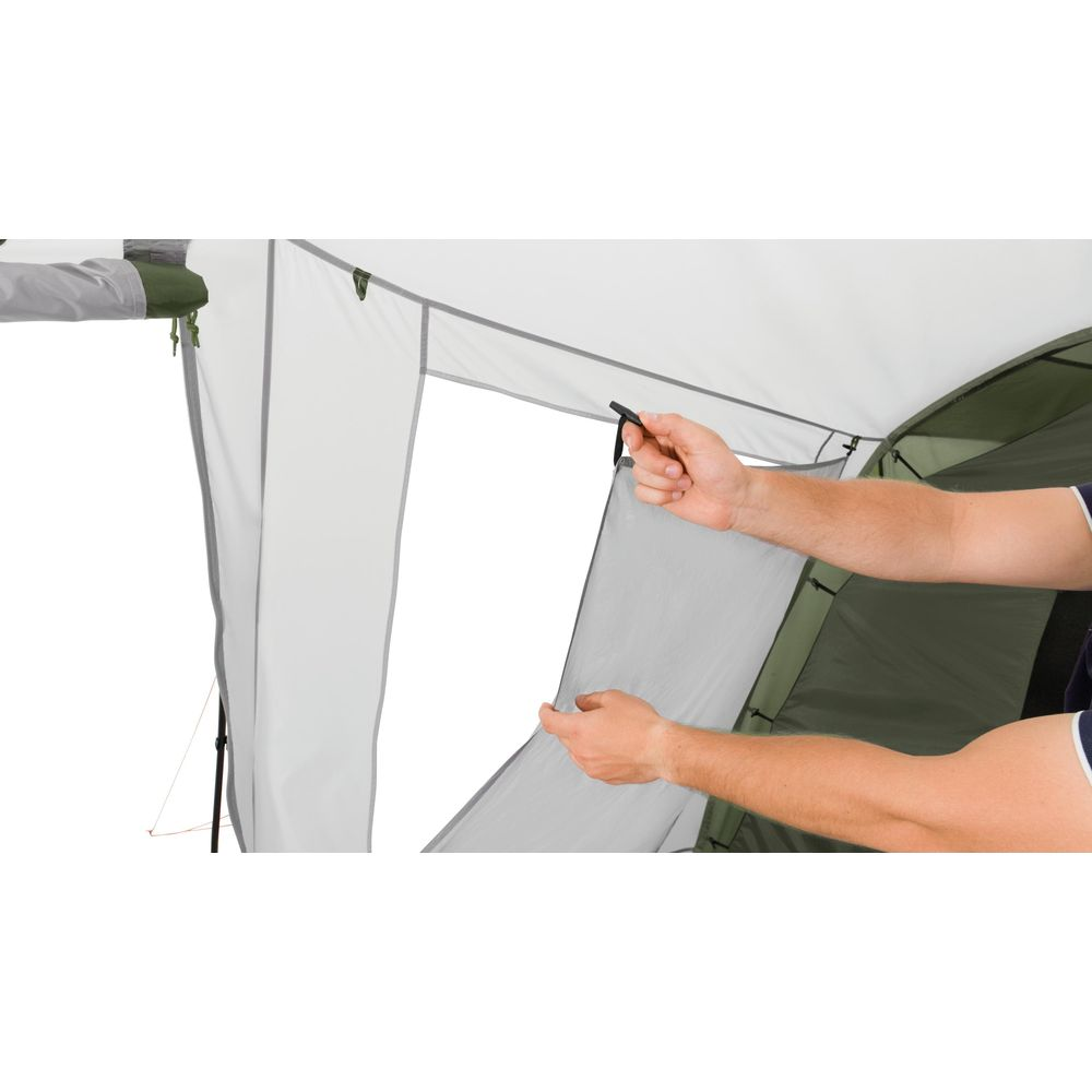 Mani che tirano giù tessuto grigio da una tenda verde.