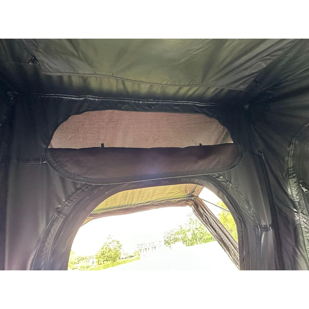 Vista attraverso una tenda con finestra a rete e porta aperta verso gli alberi.