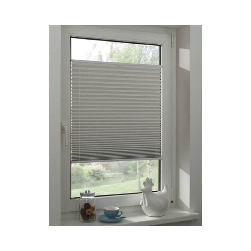 Graue Plissees über einem Fenster mit Blick auf Bäume. Auf dem Sims stehen eine Hühnerfigur, Tasse und Keksdose.