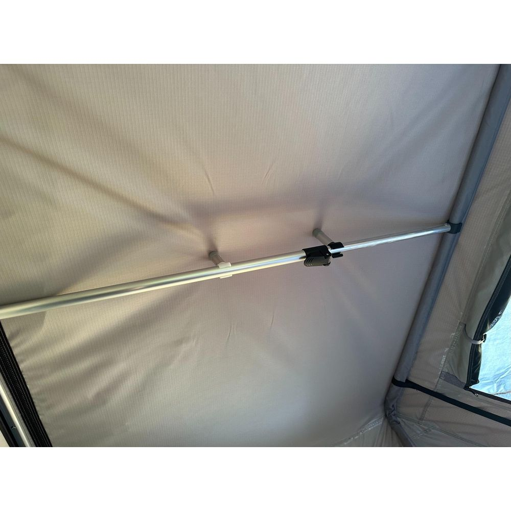 Vista interna di una tenda con pali in alluminio e soffitto in tessuto grigio.