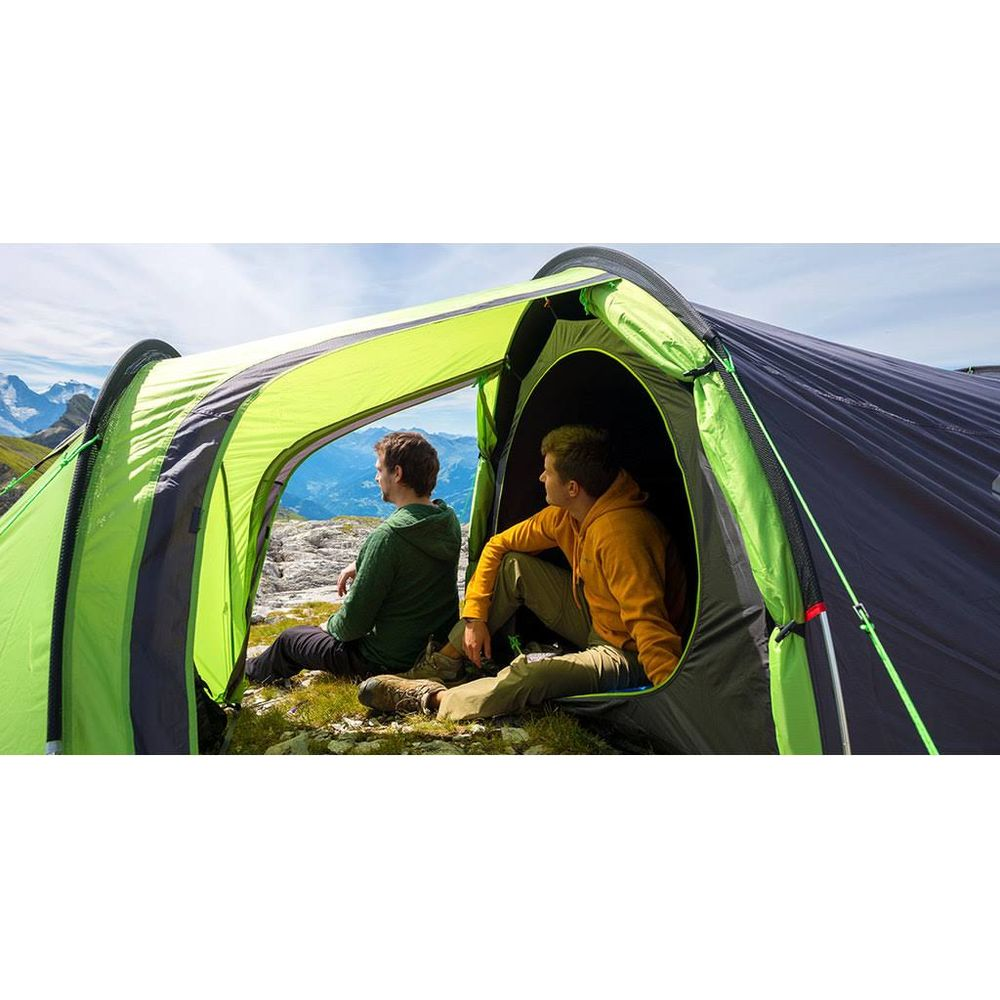 Due uomini seduti in una tenda guardano le montagne.