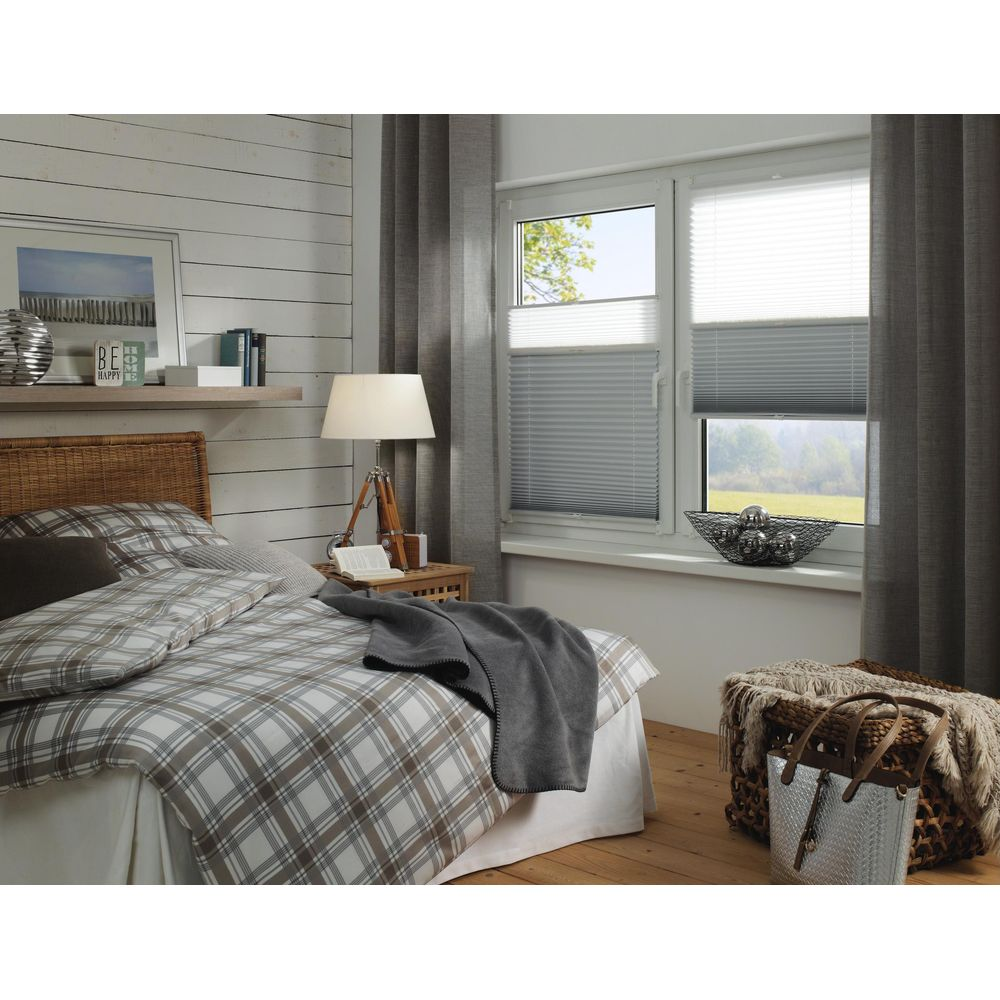 Ein Schlafzimmer mit karierter Bettwäsche, einem Nachttisch, einer Lampe und einem Fenster mit Jalousien.
