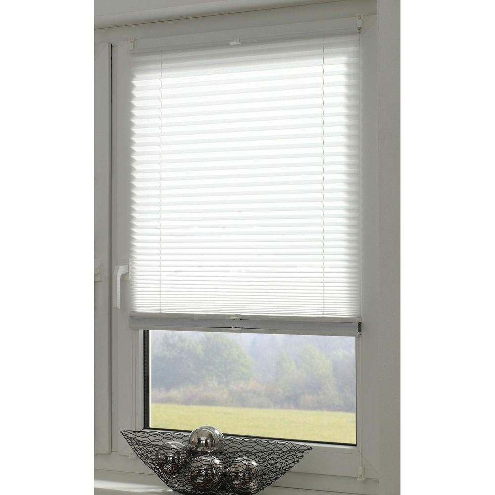Ein Fenster mit weißen Plissees, draußen grüne Bäume und eine Wiese.