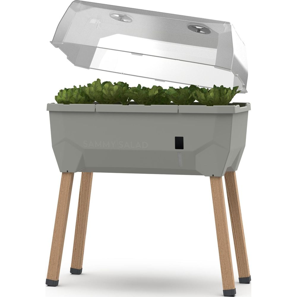 Une jardinière grise avec des plantes et un couvercle transparent sur pieds en bois.