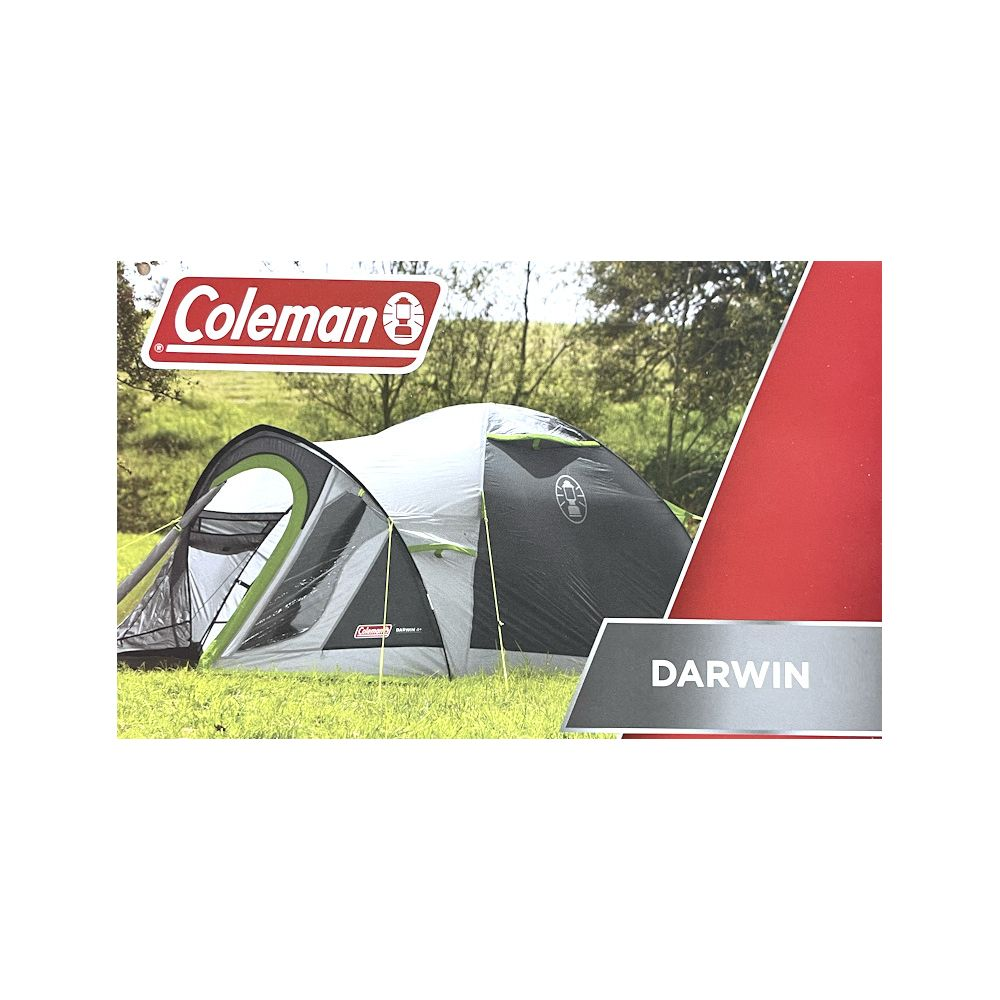 Una tenda Coleman Darwin grigia e bianca su un campo erboso verde con alberi sullo sfondo.