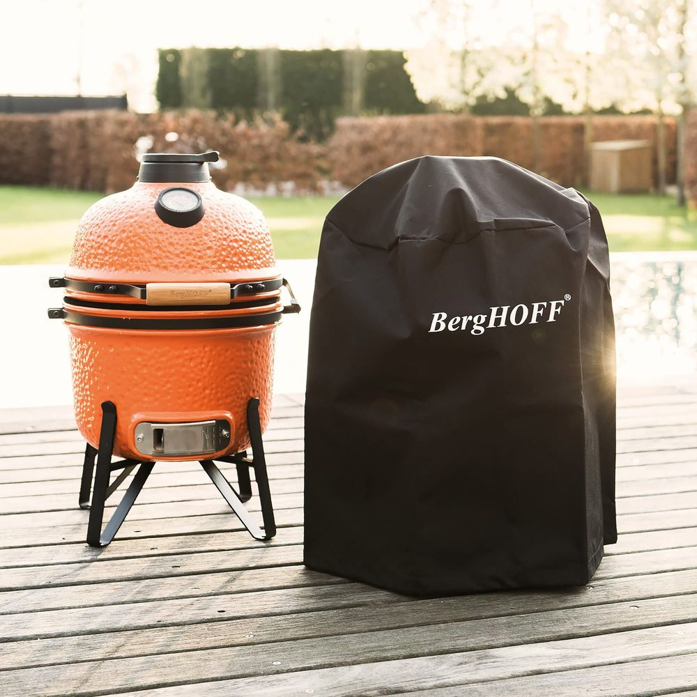 Un barbecue orange à côté d'une housse noire sur une terrasse en bois.