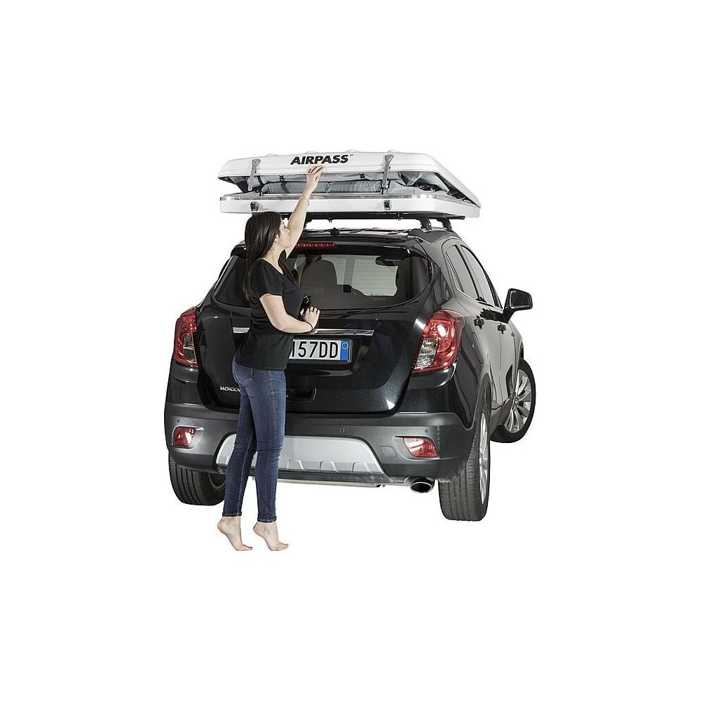Una donna chiude una tenda da tetto bianca su un'auto nera.