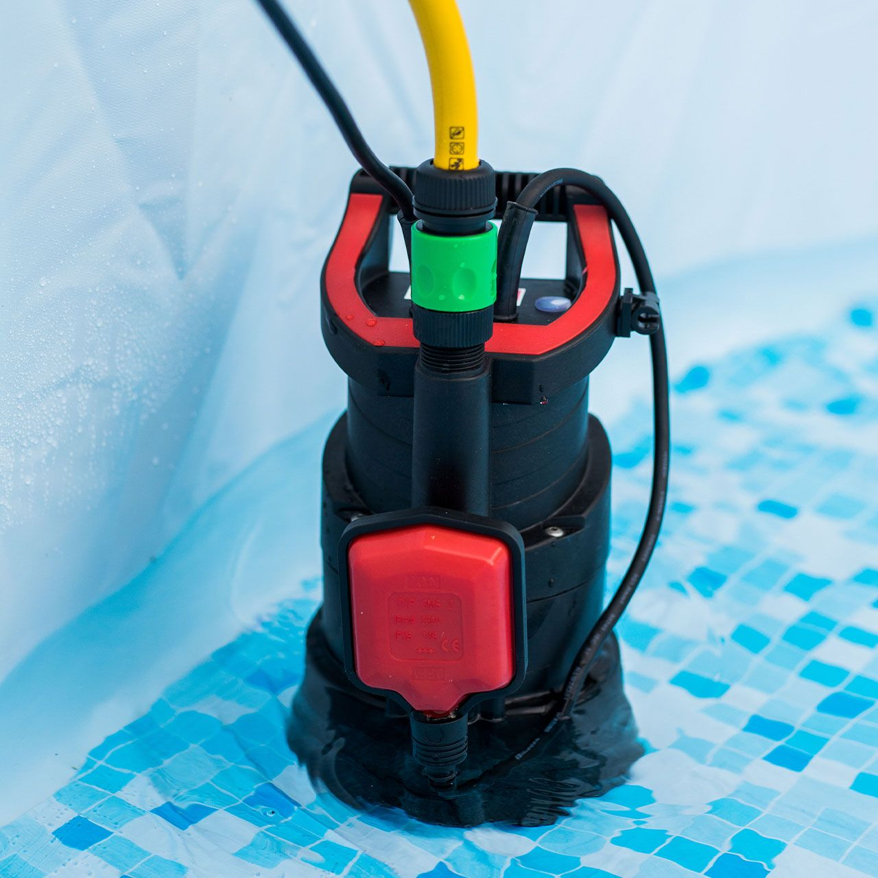 Eine schwarze und rote Tauchpumpe mit gelbem Schlauch befindet sich in klarem blauen Wasser.