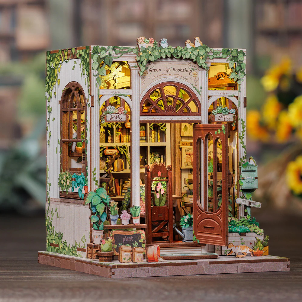 Miniatur-Buchhandlung mit Pflanzen und Lichtern, Katze liegt draußen.