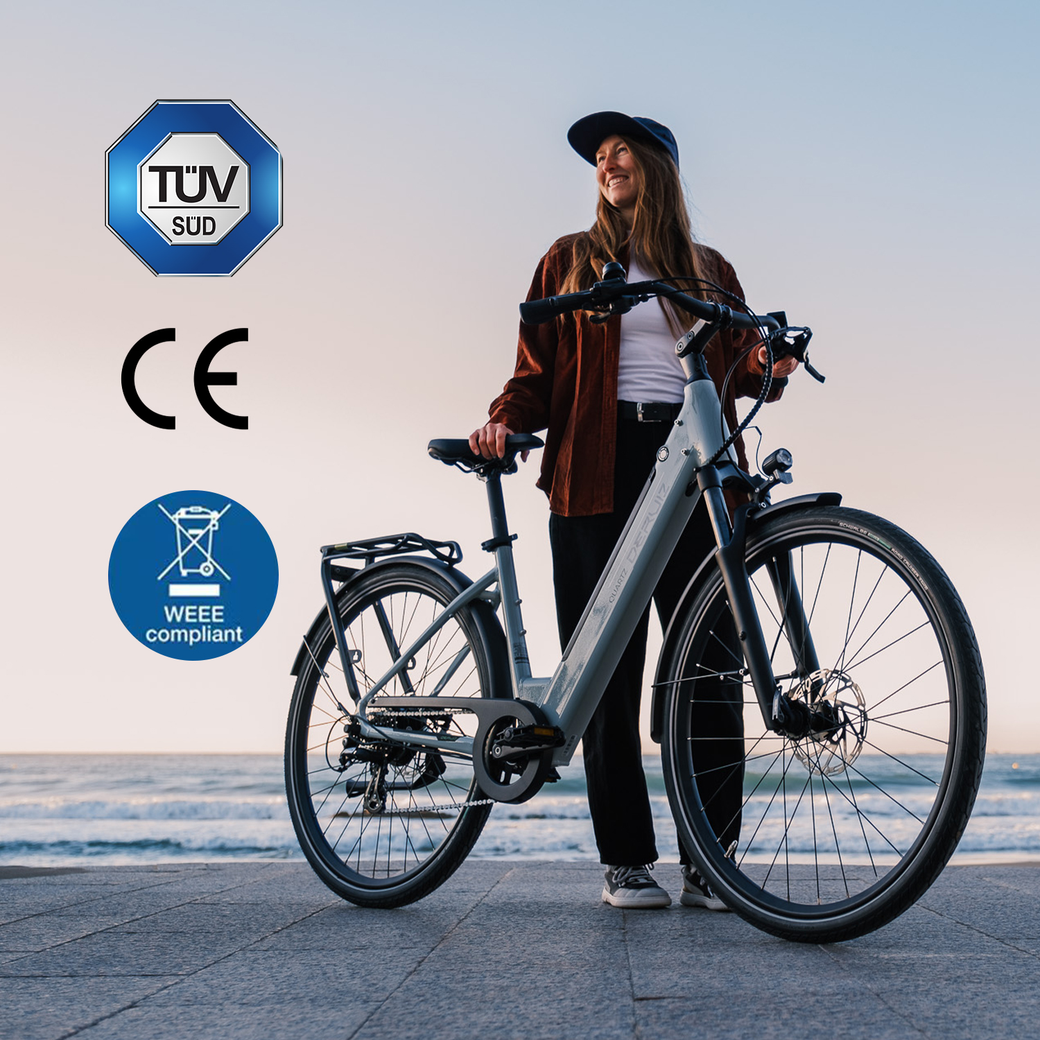 Eine Frau mit einem Fahrrad am Strand bei Sonnenuntergang, TUV Sud und CE Zeichen.