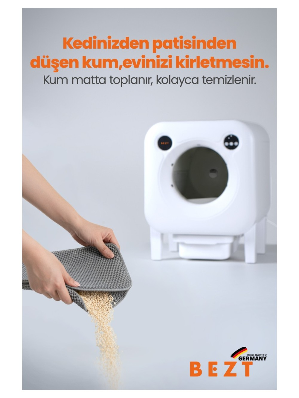 Bir el, kedi kumunun döküldüğü gri bir paspas tutuyor. Beyaz bir kedi tuvaleti.