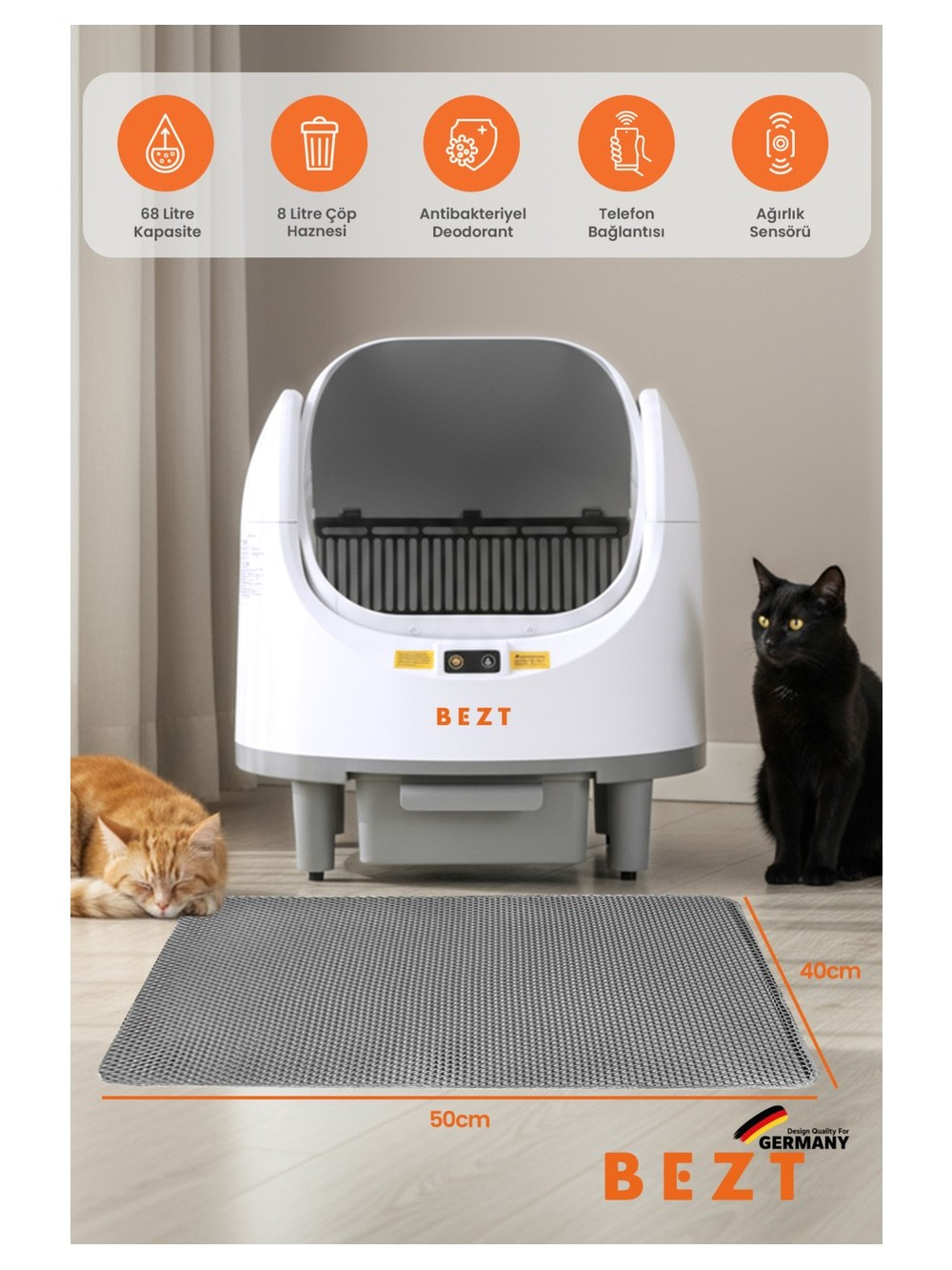 Yakınında iki kedi bulunan beyaz otomatik kedi tuvalet kabini. Önünde bir mat serilmiş.