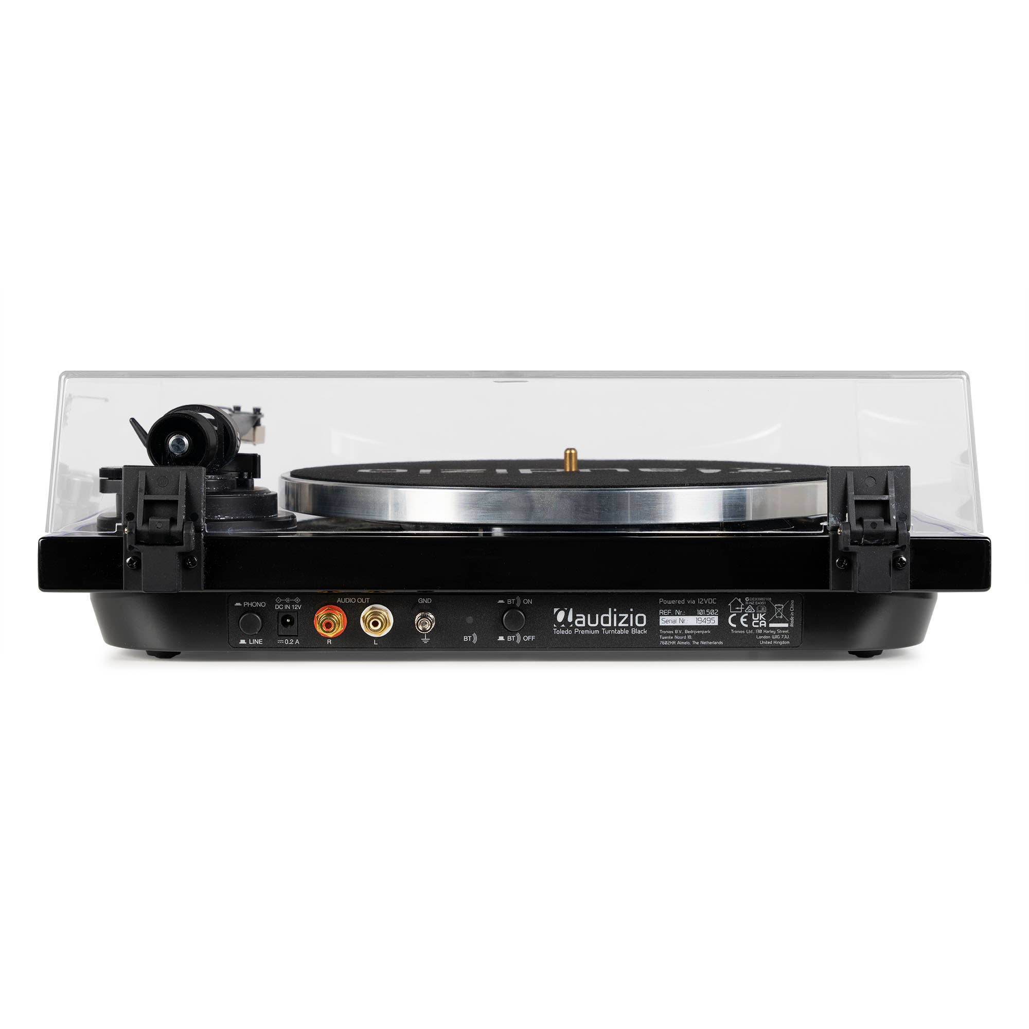Tocadiscos negro con tapa transparente y brazo de tono. Conexiones y controles en la parte trasera.