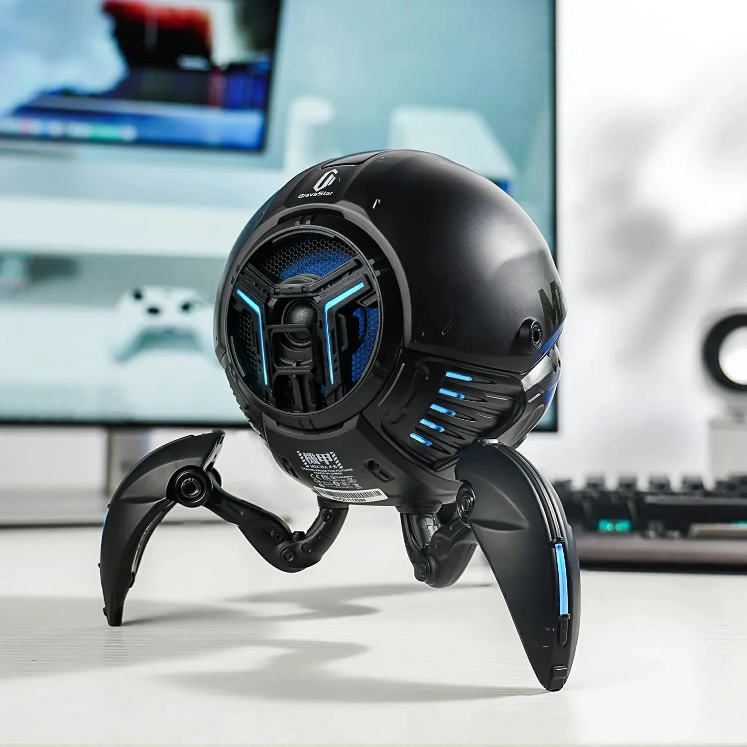 Czarny głośnik w kształcie pająka z niebieskimi akcentami stoi na stole.