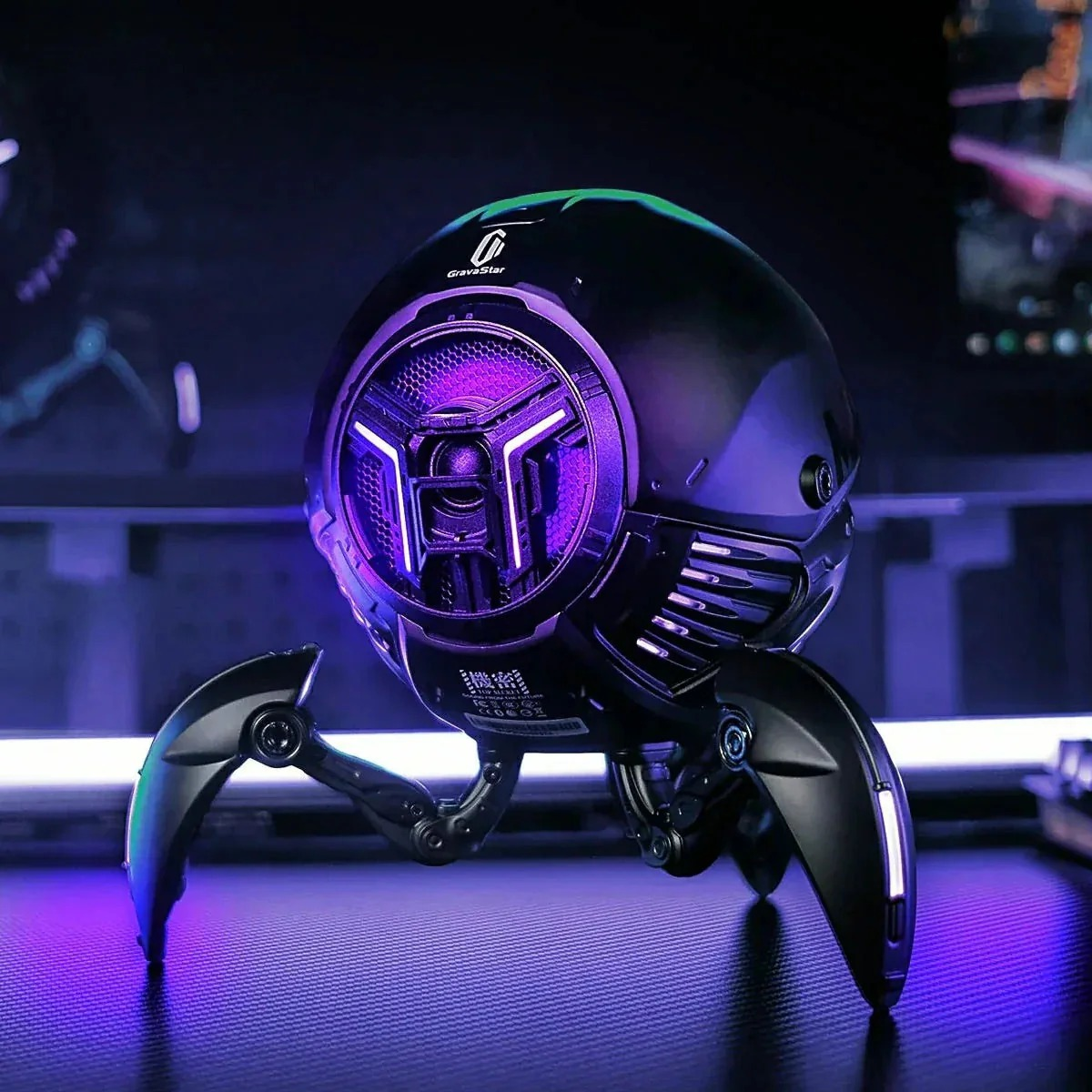 Czarny, kulisty głośnik z fioletowym podświetleniem i trzema nogami.